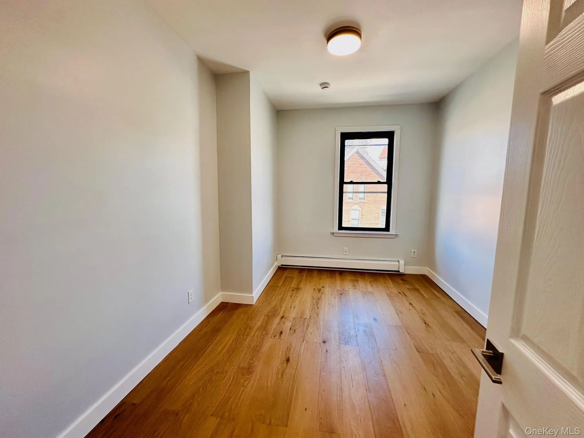 Spare room featuring light wood-style flooring and baseboard heating Spare room featuring light wood-style flooring and baseboard heating