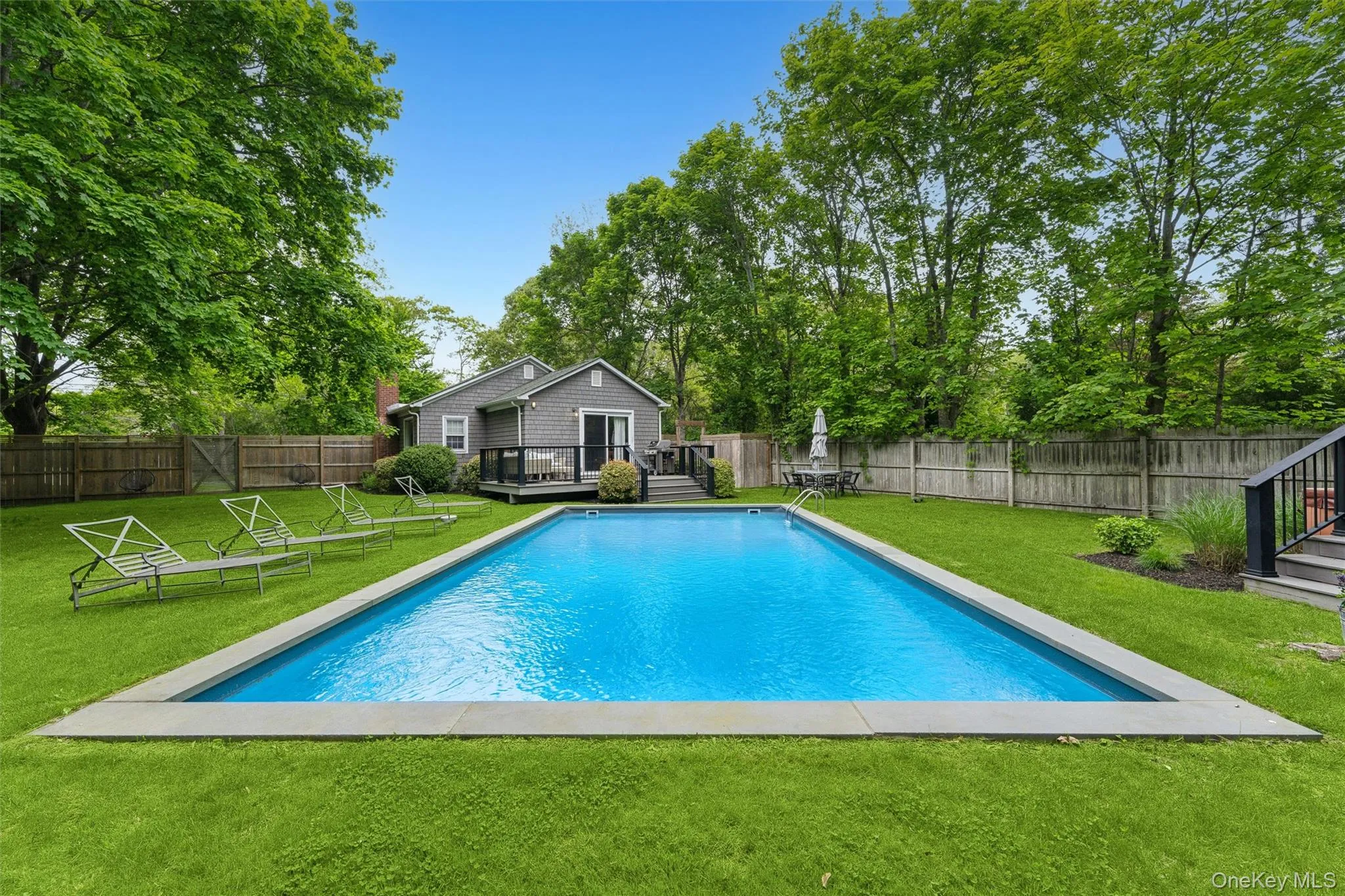 View of pool with a deck and view of scattered trees View of pool with a deck and view of scattered trees