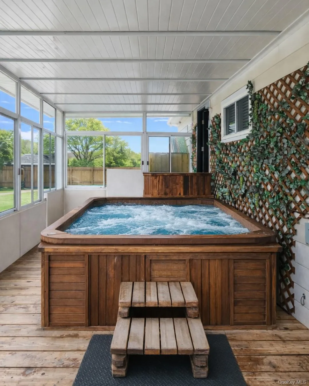 Wooden deck with a hot tub and a sunroom Wooden deck with a hot tub and a sunroom