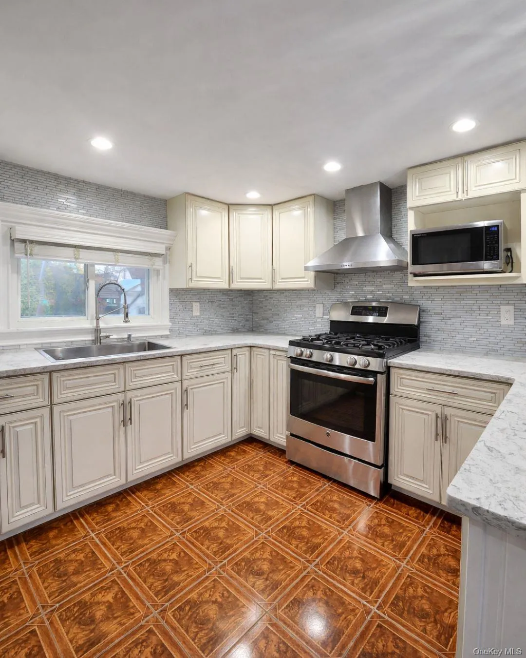 Kitchen featuring appliances with stainless steel finishes, wall chimney range hood, light stone counters, backsplash, and recessed lighting Kitchen featuring appliances with stainless steel finishes, wall chimney range hood, light stone counters, backsplash, and recessed lighting