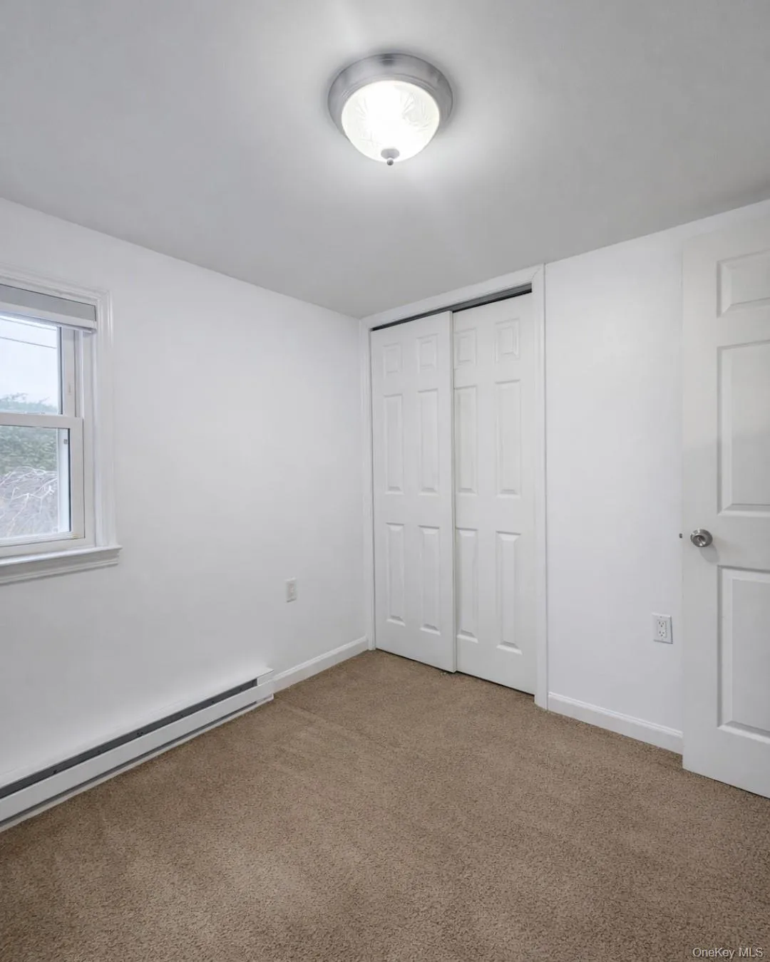 Unfurnished bedroom featuring a baseboard radiator, carpet, and a closet Unfurnished bedroom featuring a baseboard radiator, carpet, and a closet