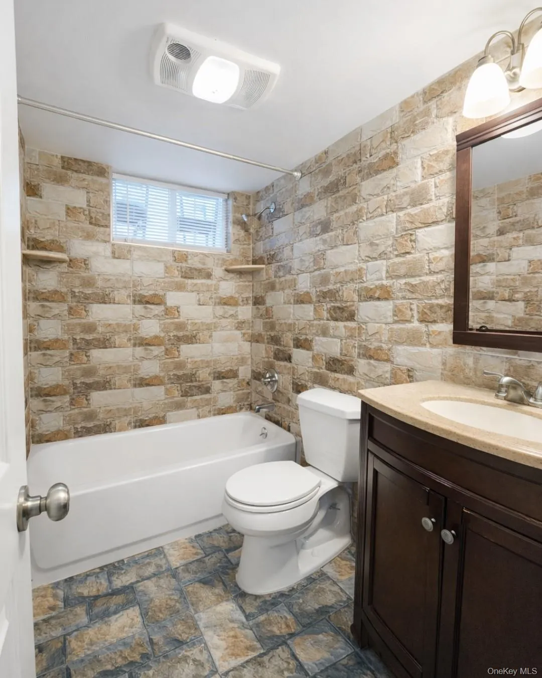 Bathroom featuring tub / shower combination, vanity, and stone finish floors Bathroom featuring tub / shower combination, vanity, and stone finish floors