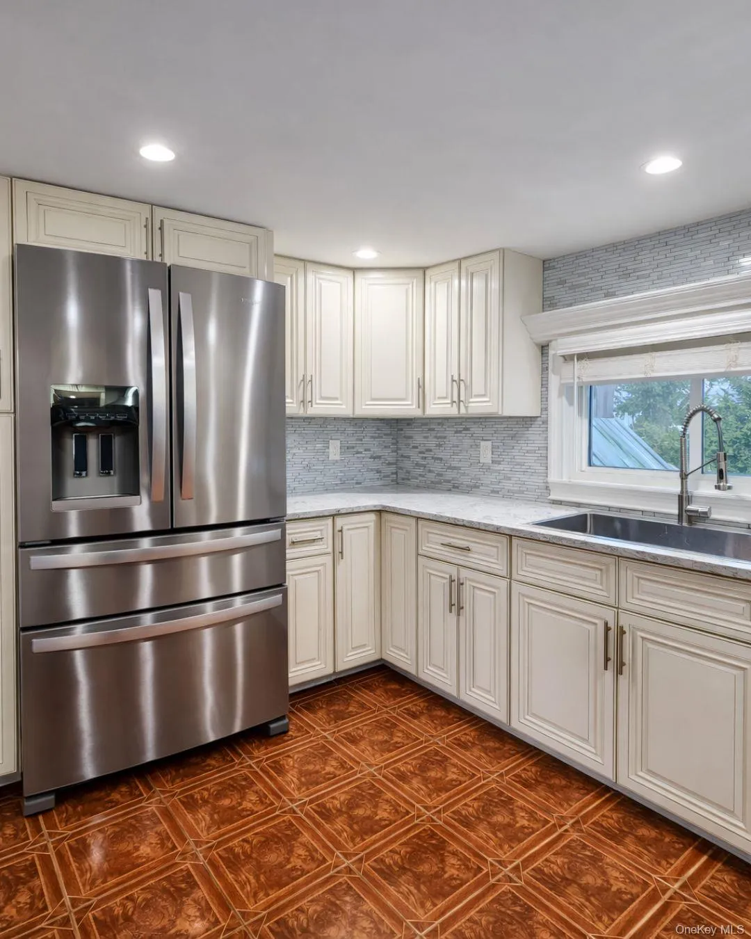 Kitchen with stainless steel fridge, light stone countertops, cream cabinetry, tasteful backsplash, and recessed lighting Kitchen with stainless steel fridge, light stone countertops, cream cabinetry, tasteful backsplash, and recessed lighting