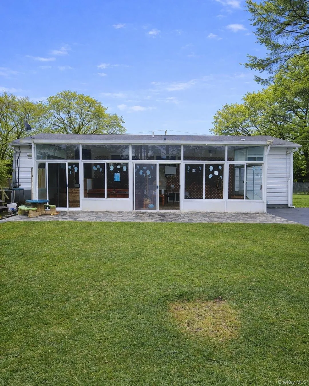 Back of house with a sunroom, a lawn, and a patio Back of house with a sunroom, a lawn, and a patio