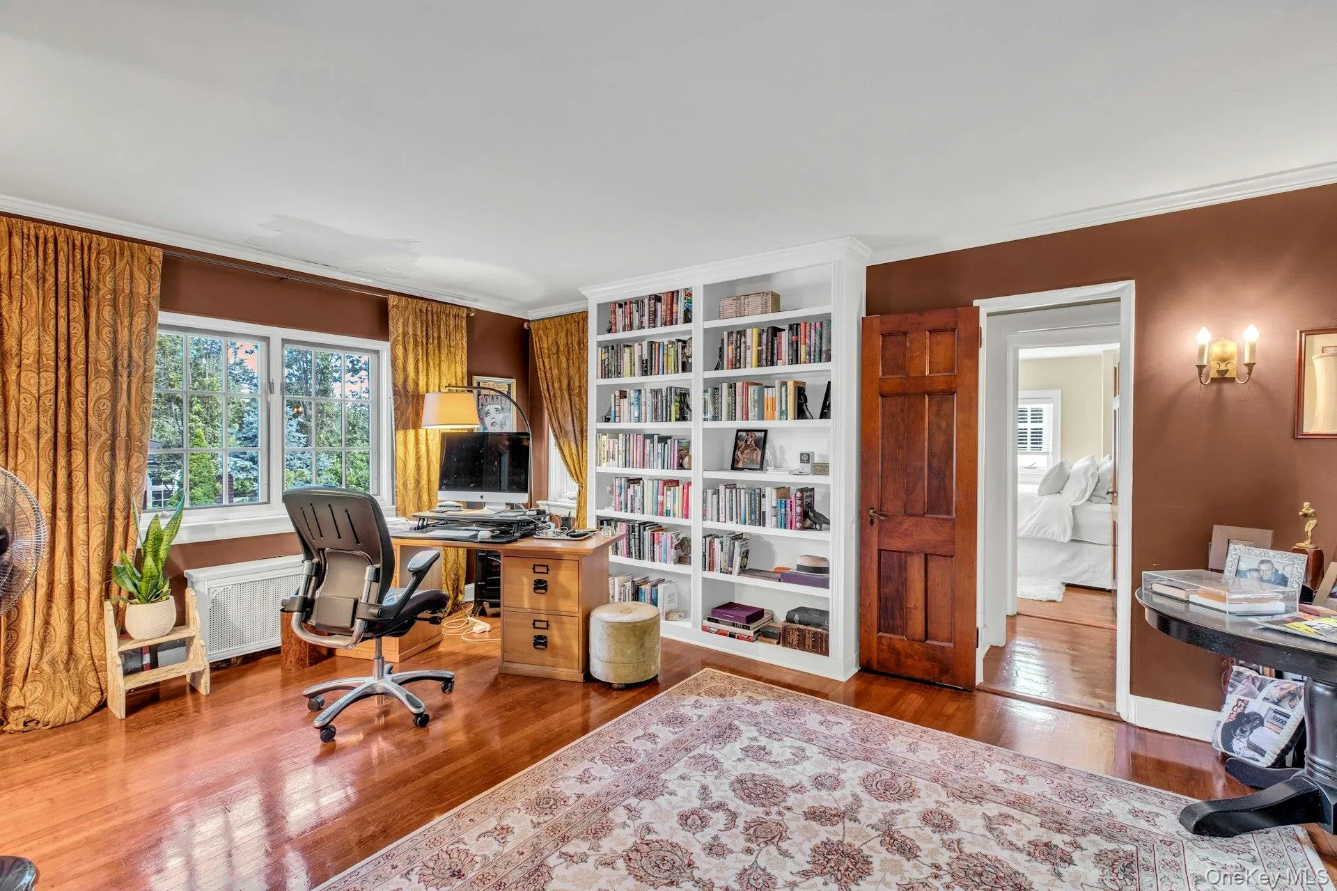 Guest bedroom (being used as an office) with wood floors, crown molding and built-in bookcases Guest bedroom (being used as an office) with wood floors, crown molding and built-in bookcases