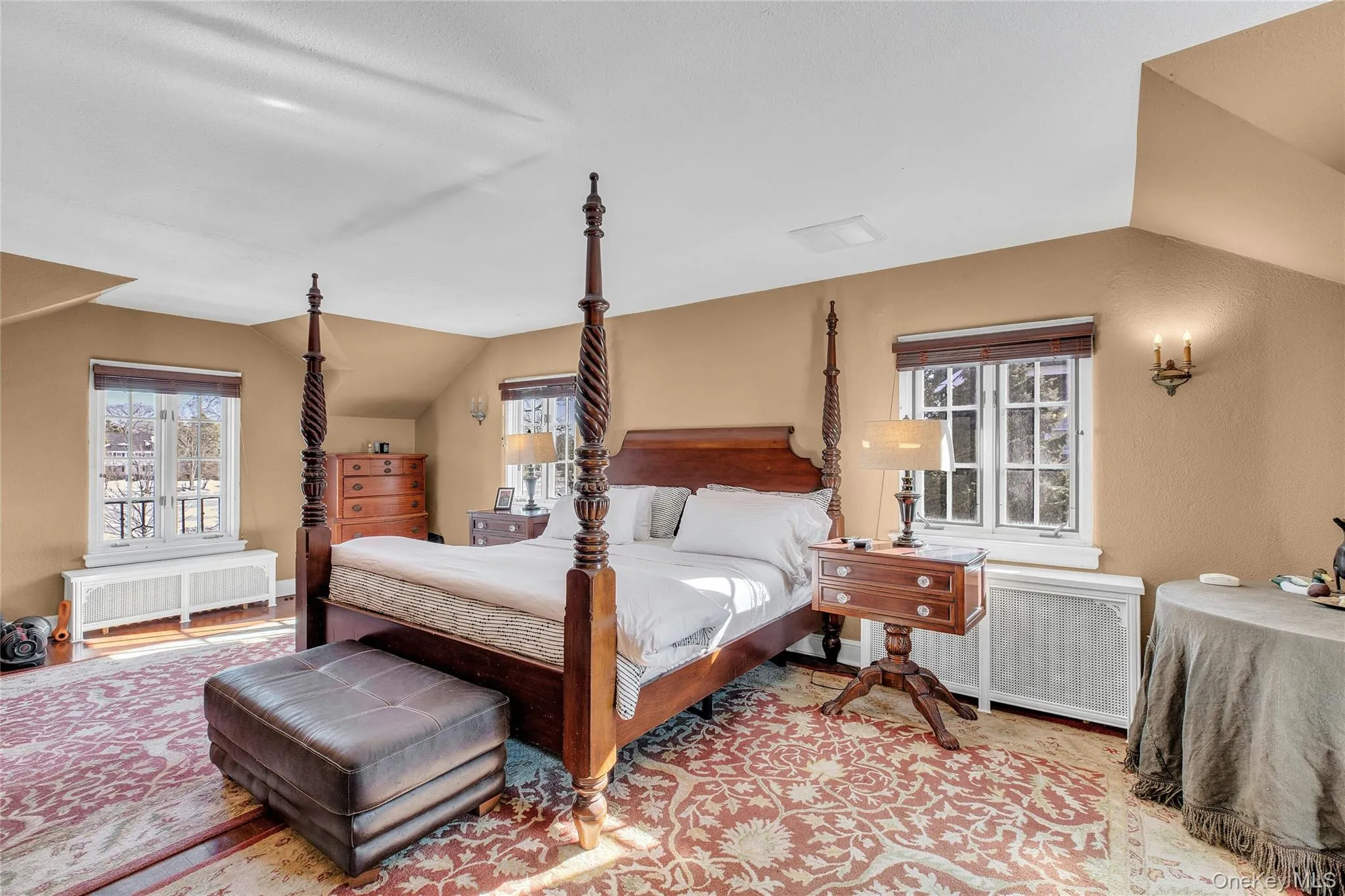 Angled ceilings, warm wall tones, two casement windows with privacy blinds, and a built-in wall sconce Angled ceilings, warm wall tones, two casement windows with privacy blinds, and a built-in wall sconce
