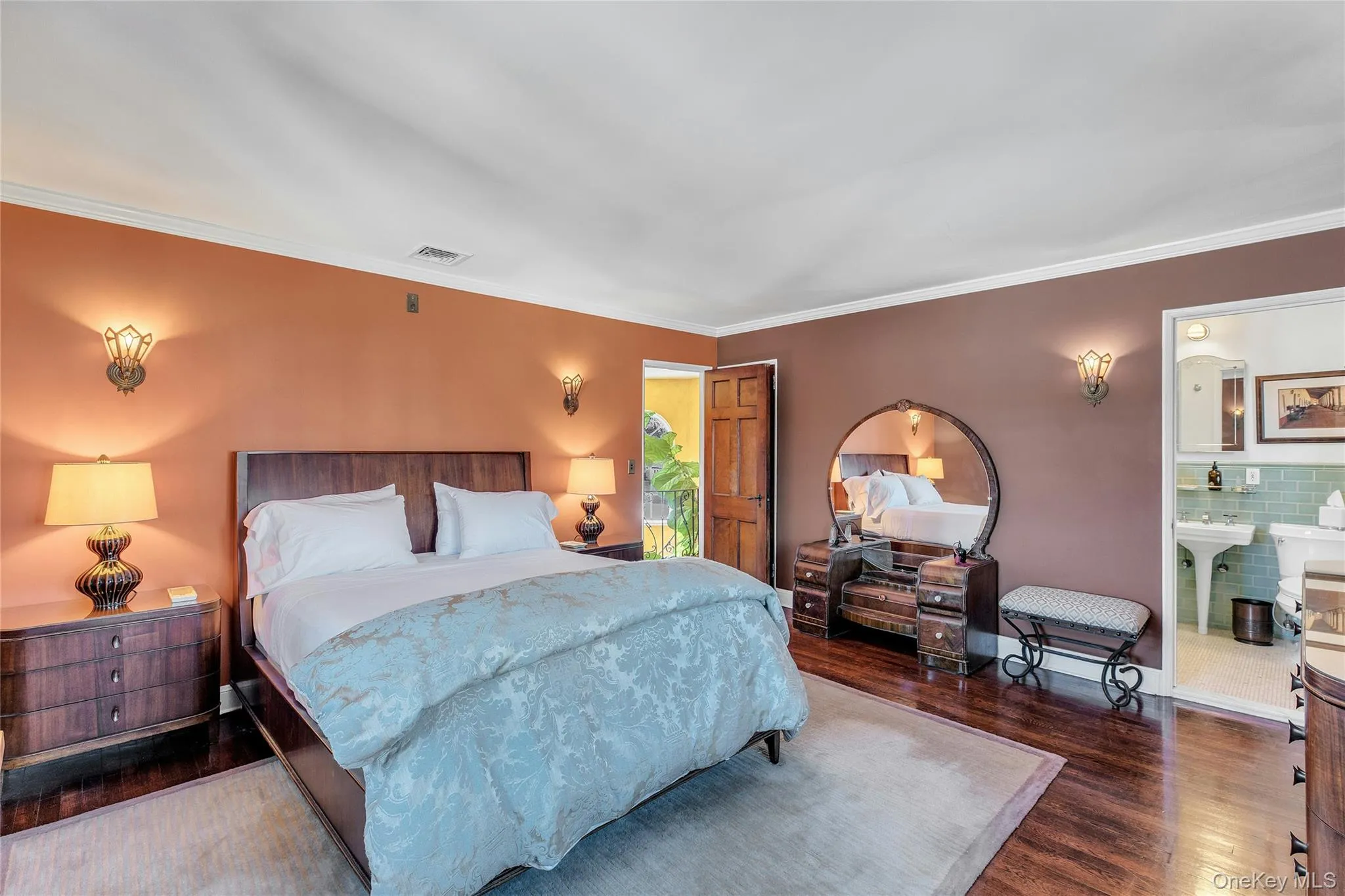 Hardwood flooring, crown molding, wall sconces, wood door, and a built-in vanity with mirror Hardwood flooring, crown molding, wall sconces, wood door, and a built-in vanity with mirror