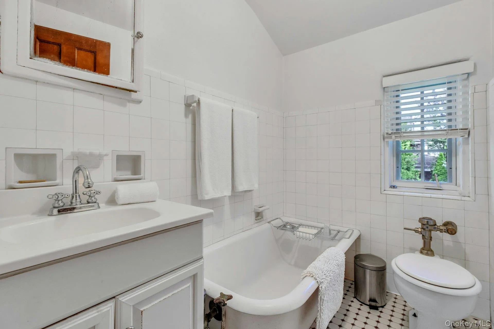 Maids quarters full bathroom featuring tile walls, vanity, a bathtub, and tile floors Maids quarters full bathroom featuring tile walls, vanity, a bathtub, and tile floors