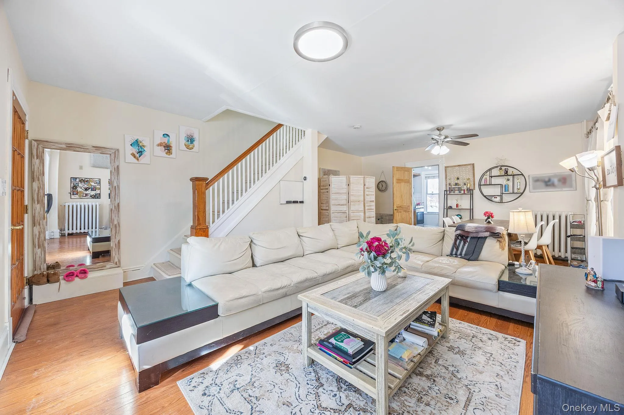 Living area with wood finished floors, radiator heating unit, ceiling fan, and stairs Living area with wood finished floors, radiator heating unit, ceiling fan, and stairs