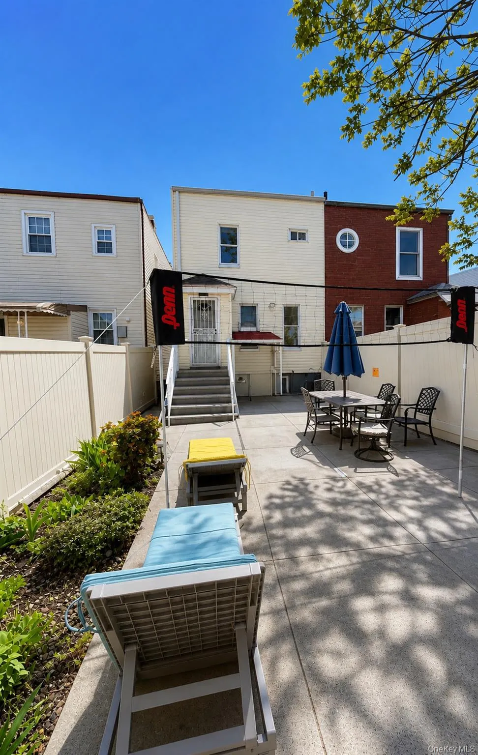 Spacious rear patio featuring a concrete surface, built-in planter with greenery, and stairs providing exterior access Spacious rear patio featuring a concrete surface, built-in planter with greenery, and stairs providing exterior access