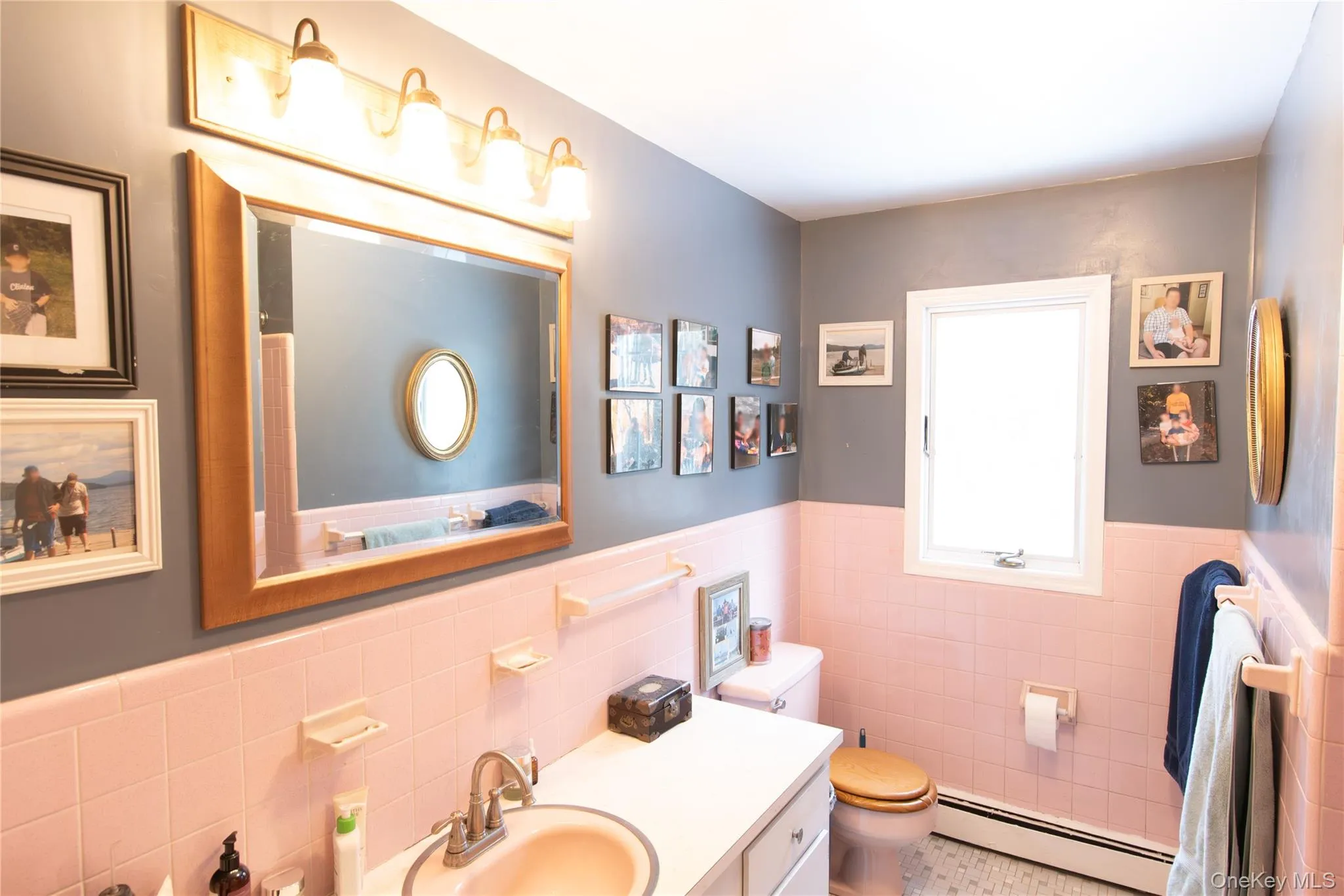 Bathroom with wainscoting, a baseboard radiator, vanity, tile walls, and tile patterned floors Bathroom with wainscoting, a baseboard radiator, vanity, tile walls, and tile patterned floors