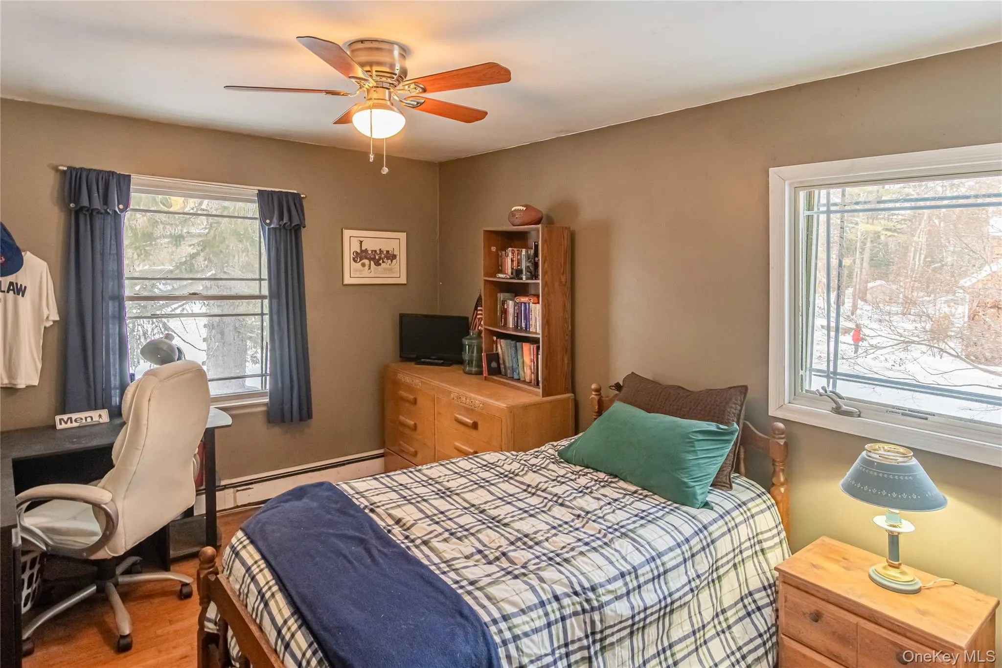 Bedroom with wood finished floors, baseboard heating, a ceiling fan, and multiple windows Bedroom with wood finished floors, baseboard heating, a ceiling fan, and multiple windows