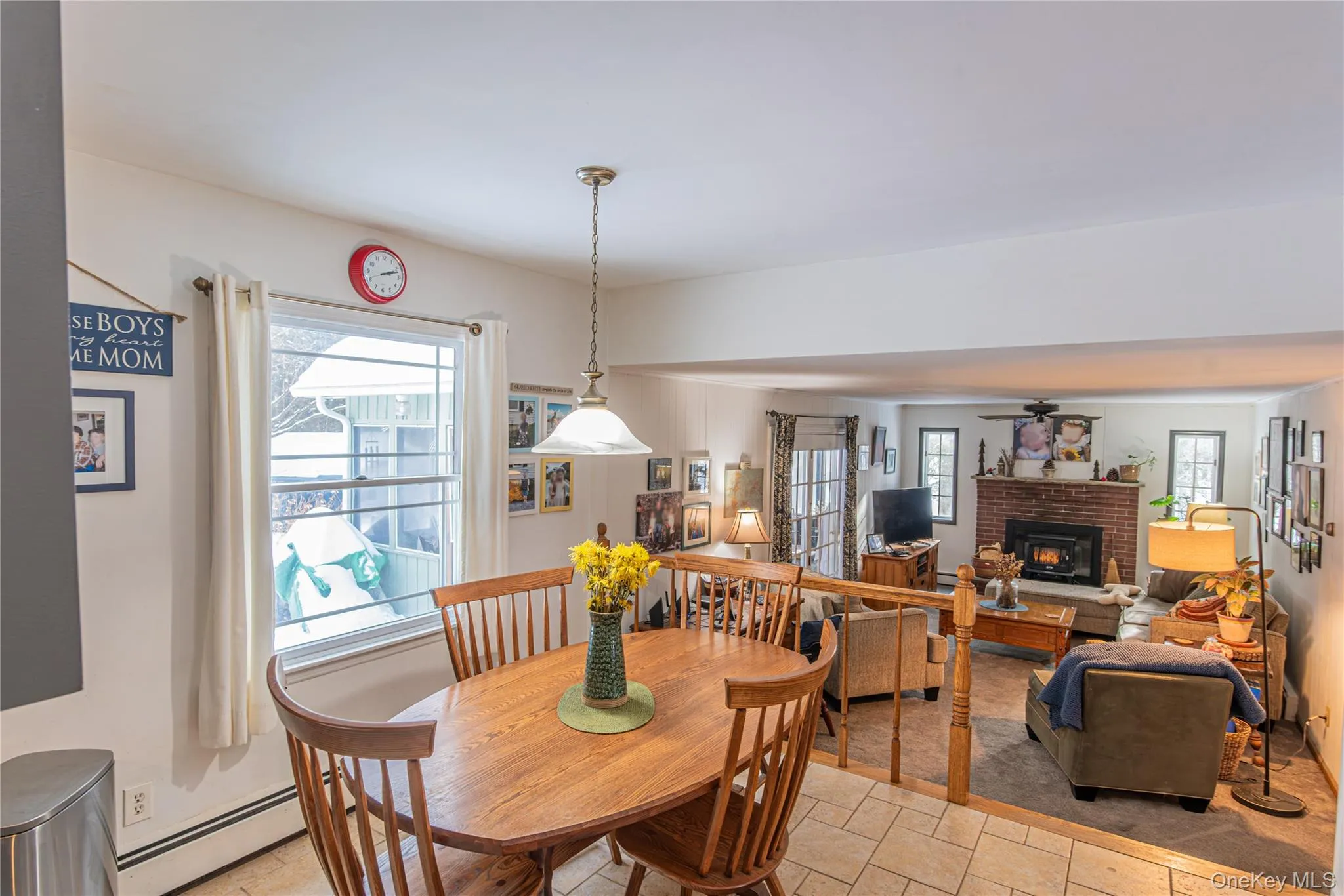 Dining room with a brick fireplace, a baseboard heating unit, healthy amount of natural light, and light stone finish floors Dining room with a brick fireplace, a baseboard heating unit, healthy amount of natural light, and light stone finish floors