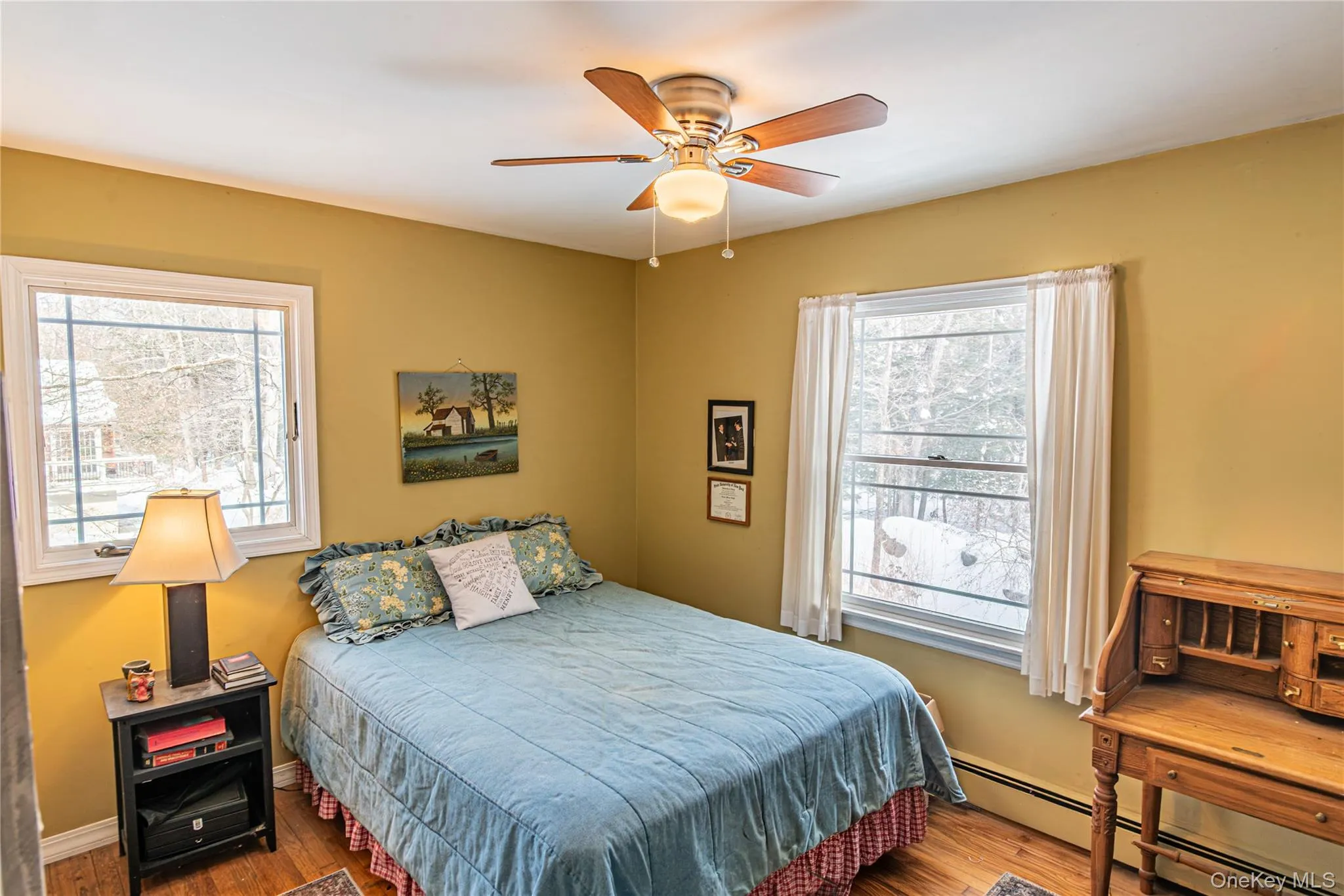 Bedroom featuring a baseboard heating unit, wood finished floors, and ceiling fan Bedroom featuring a baseboard heating unit, wood finished floors, and ceiling fan