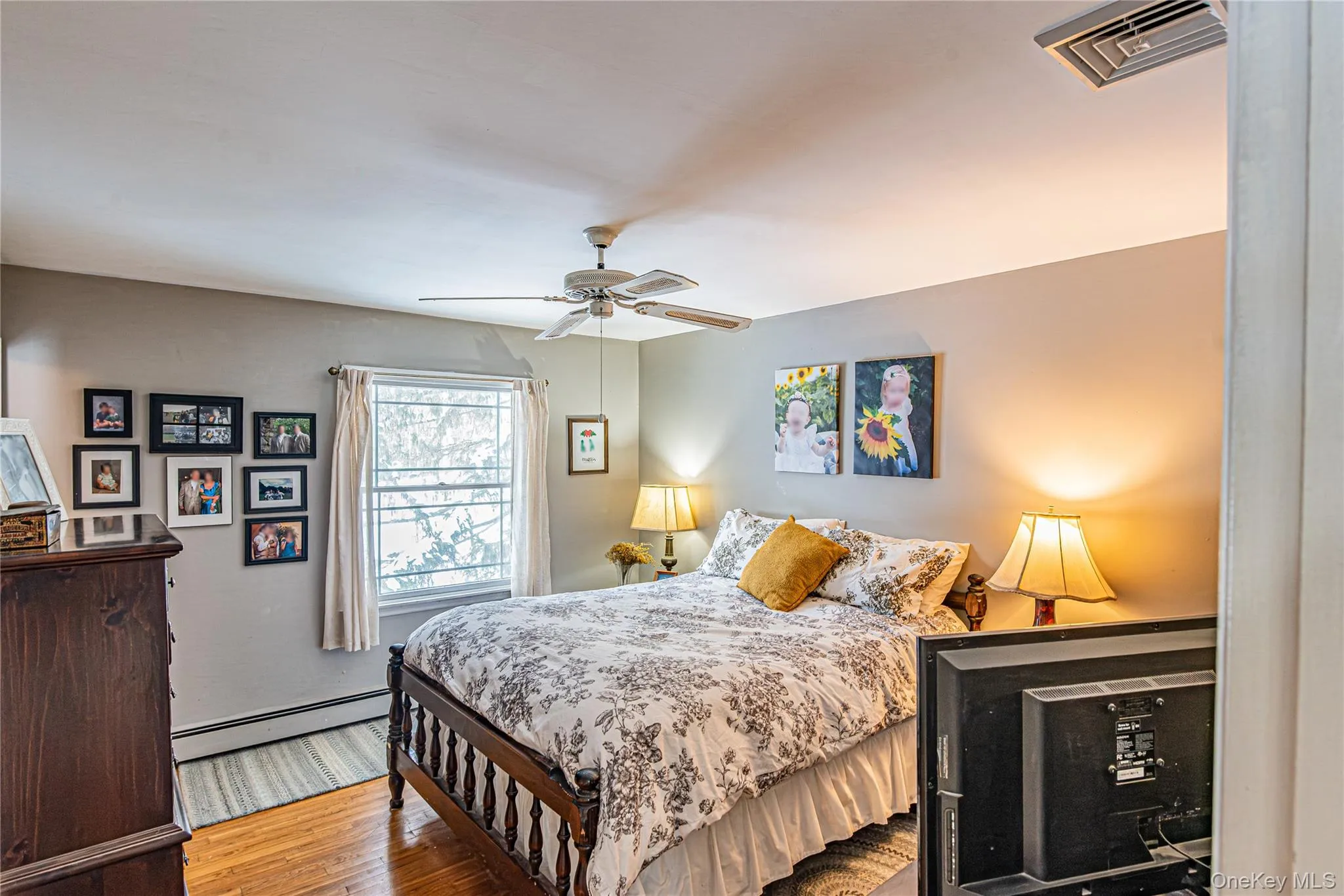 Bedroom with a baseboard radiator, wood finished floors, and a ceiling fan Bedroom with a baseboard radiator, wood finished floors, and a ceiling fan
