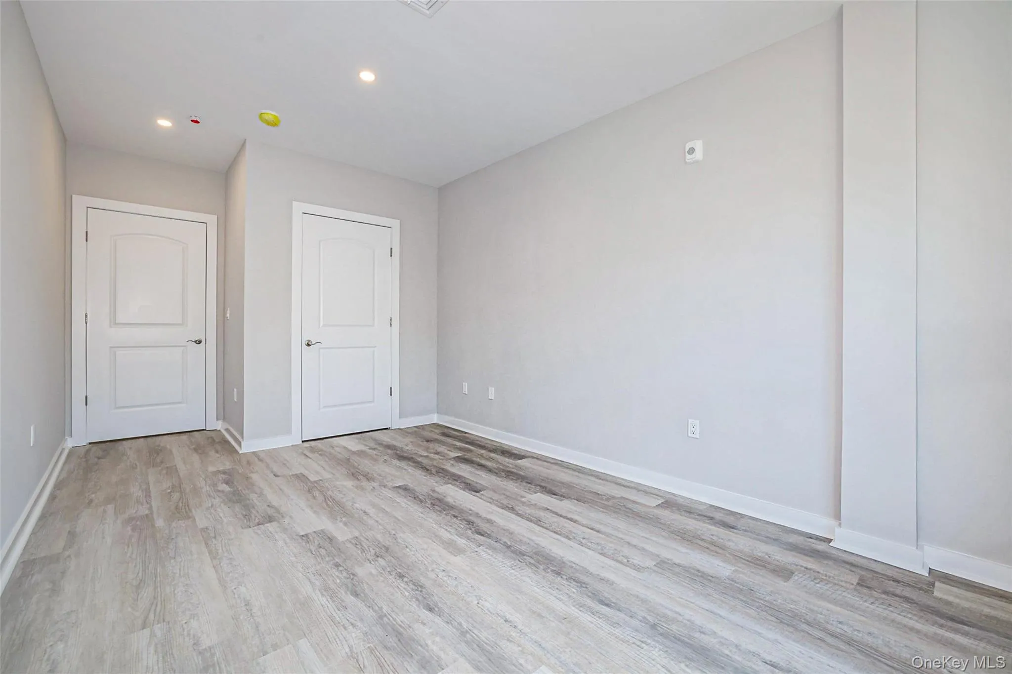 Unfurnished bedroom with light wood finished floors and recessed lighting Unfurnished bedroom with light wood finished floors and recessed lighting