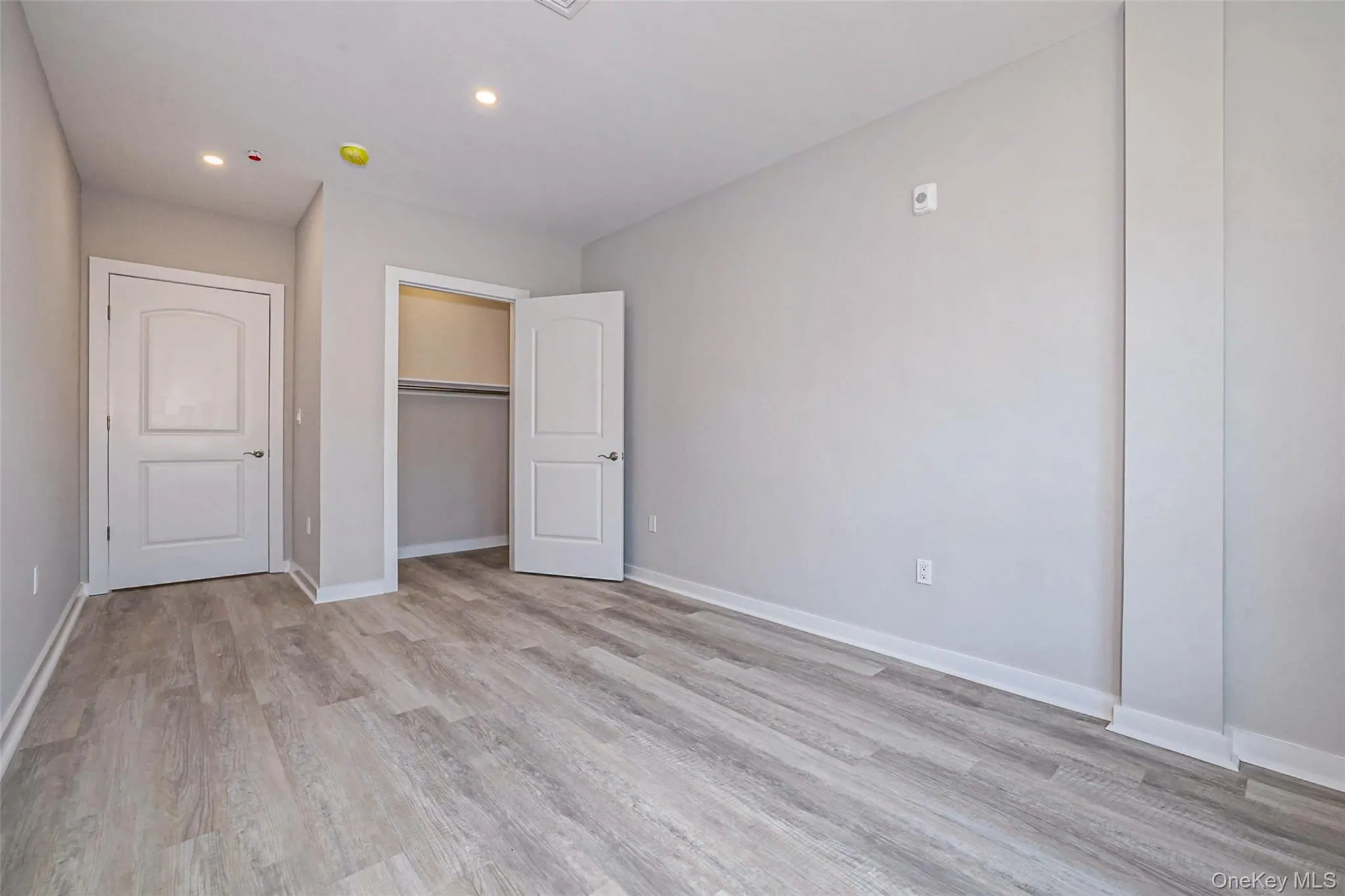 Unfurnished bedroom with light wood-style flooring, a closet, and recessed lighting Unfurnished bedroom with light wood-style flooring, a closet, and recessed lighting