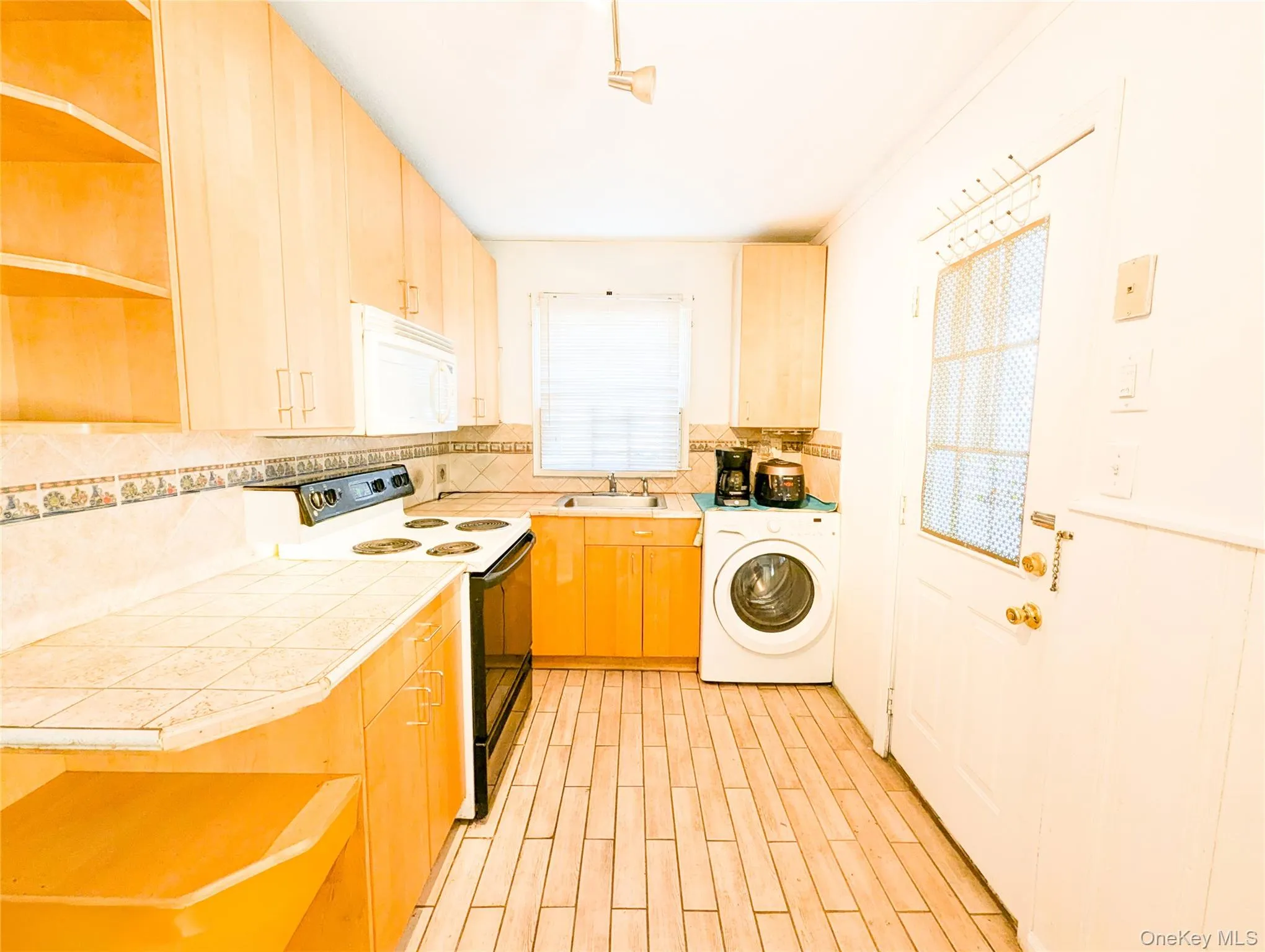 Kitchen with washer / dryer, white appliances, plenty of natural light, and sink Kitchen with washer / dryer, white appliances, plenty of natural light, and sink