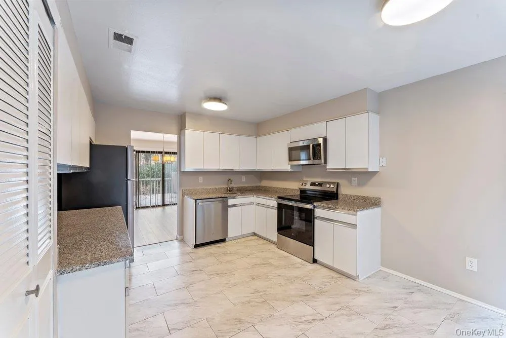 Kitchen featuring stainless steel appliances, white cabinetry, and dark stone counters Kitchen featuring stainless steel appliances, white cabinetry, and dark stone counters