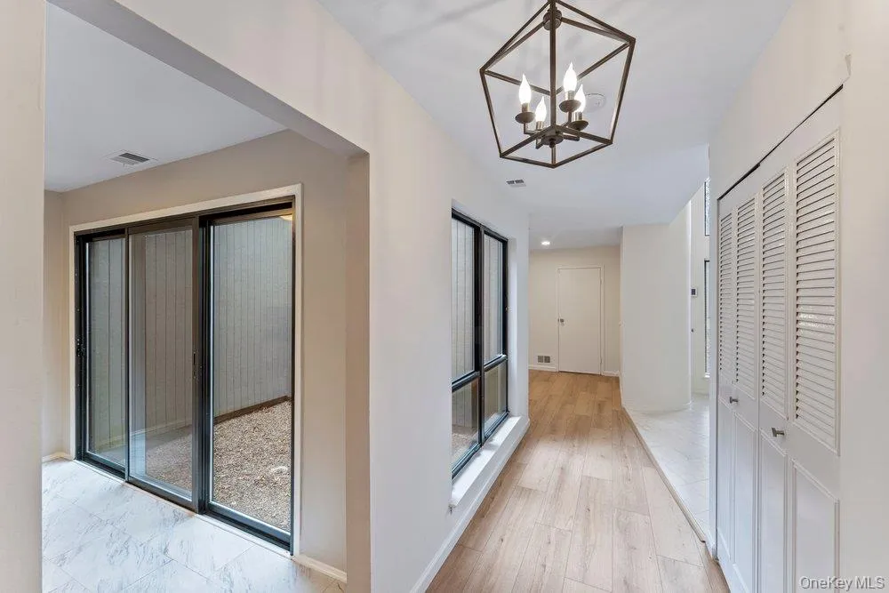 Hallway with suspended lighting and light wood-type flooring Hallway with suspended lighting and light wood-type flooring