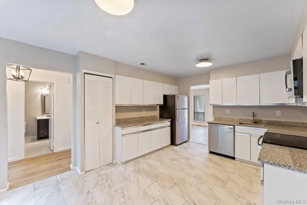 Kitchen with white cabinets, light stone counters, and stainless steel appliances Kitchen with white cabinets, light stone counters, and stainless steel appliances