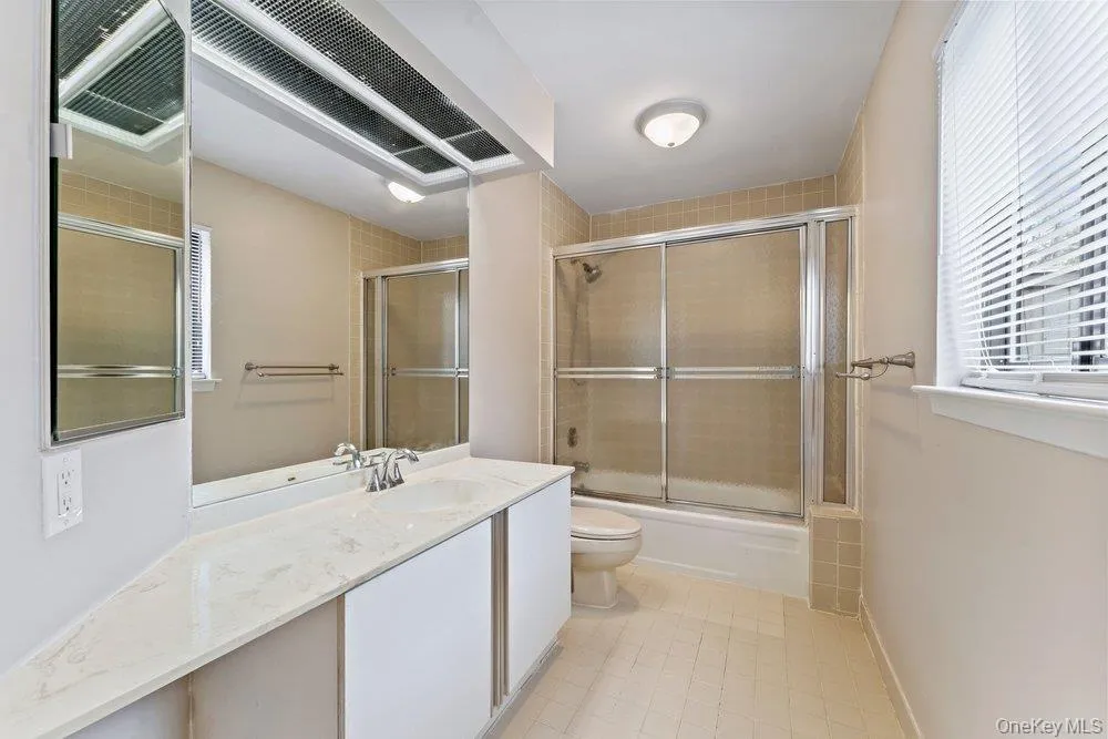 Full bathroom featuring vanity, combined bath / shower with glass door, and light tile patterned floors Full bathroom featuring vanity, combined bath / shower with glass door, and light tile patterned floors