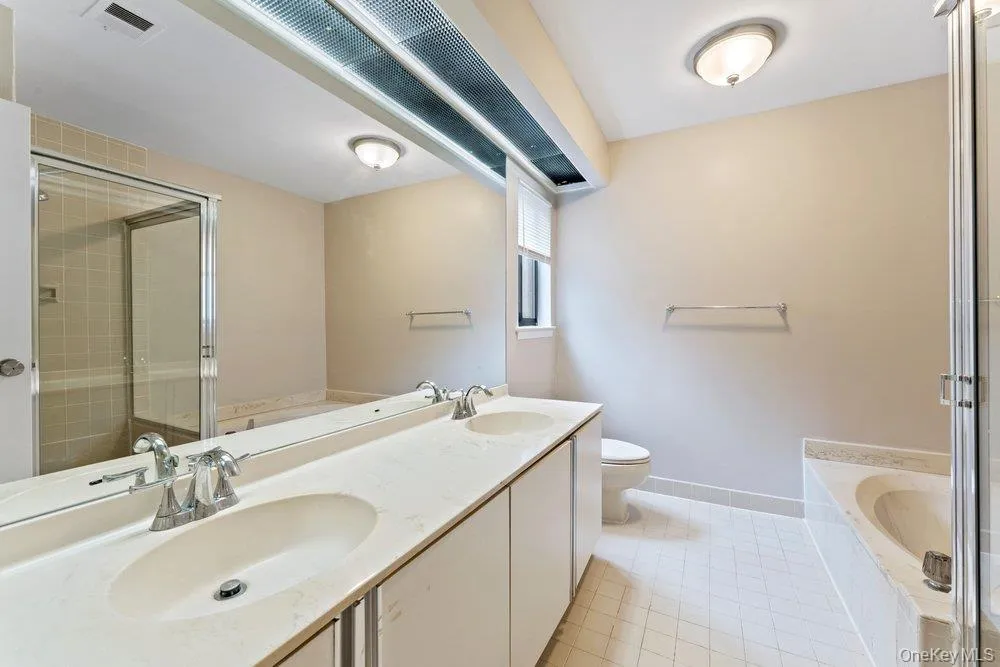Full bath featuring a garden tub, double vanity, a stall shower, and light tile patterned floors Full bath featuring a garden tub, double vanity, a stall shower, and light tile patterned floors