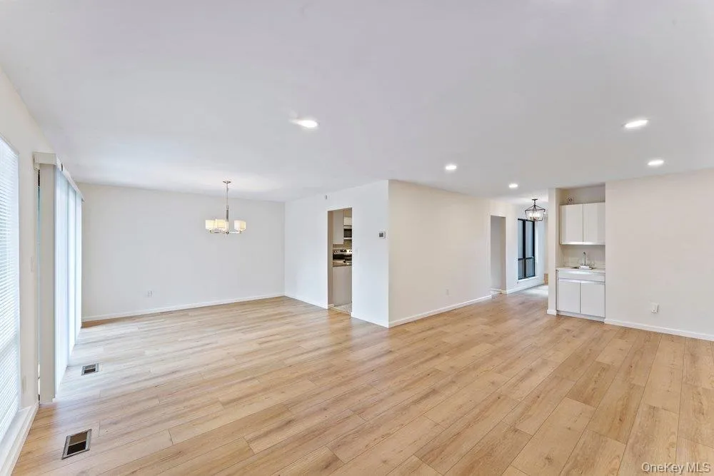 Unfurnished living room featuring hanging lights and light wood-style flooring Unfurnished living room featuring hanging lights and light wood-style flooring