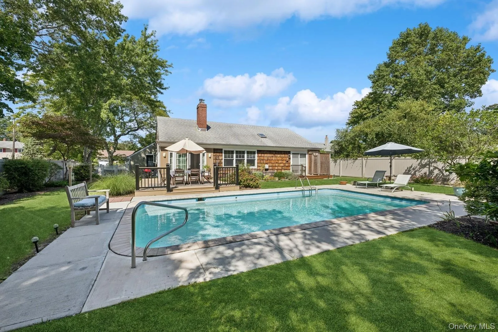 View of pool featuring the yard, deck, and seating areas View of pool featuring the yard, deck, and seating areas