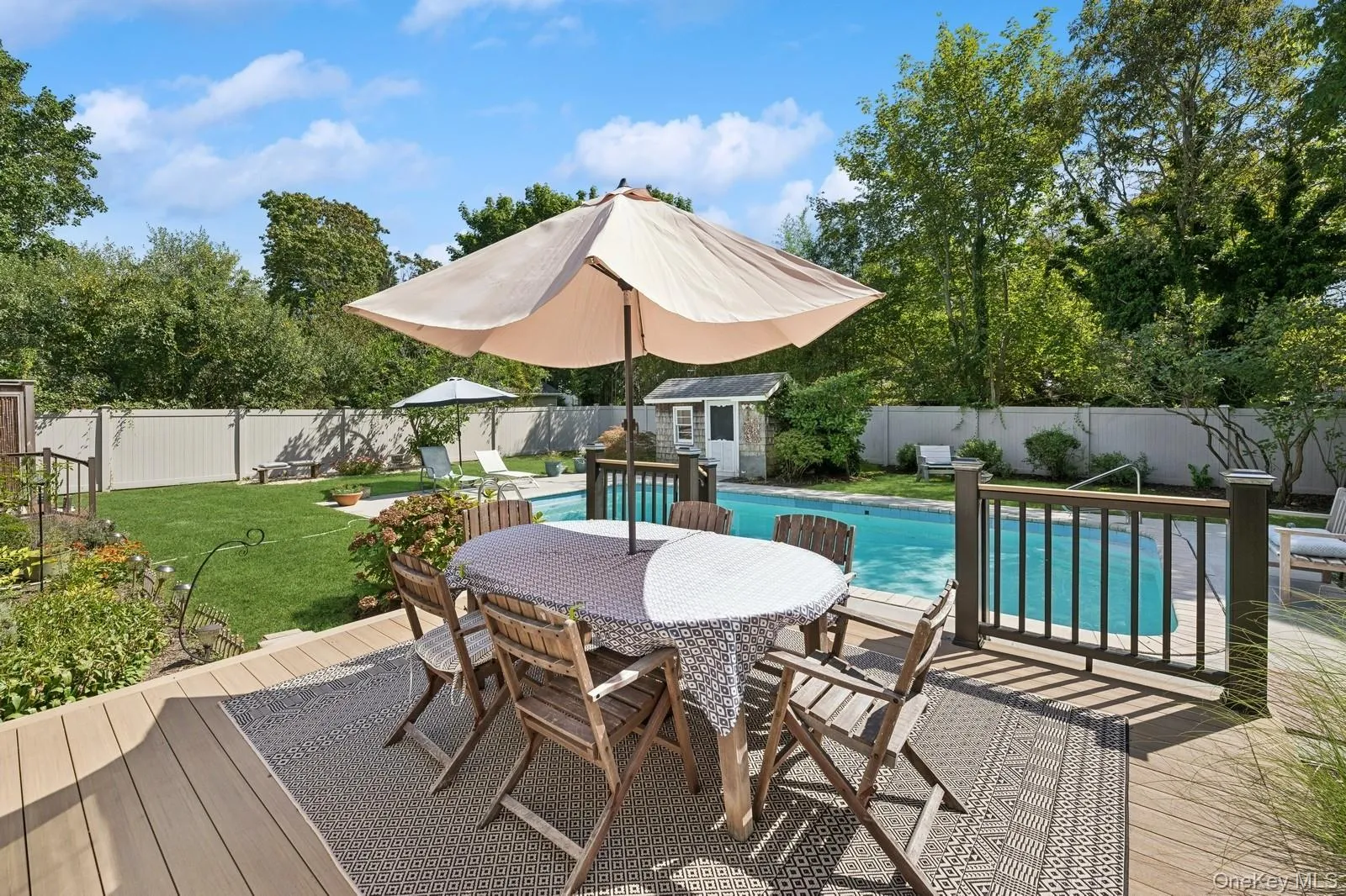 Dining on the new wooden deck with a fenced-in pool and yard. Dining on the new wooden deck with a fenced-in pool and yard.