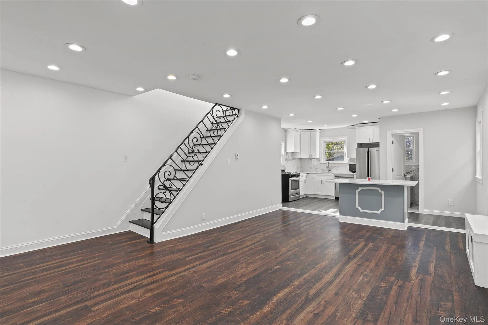 Unfurnished living room featuring stairs, dark wood-style floors, and recessed lighting Unfurnished living room featuring stairs, dark wood-style floors, and recessed lighting