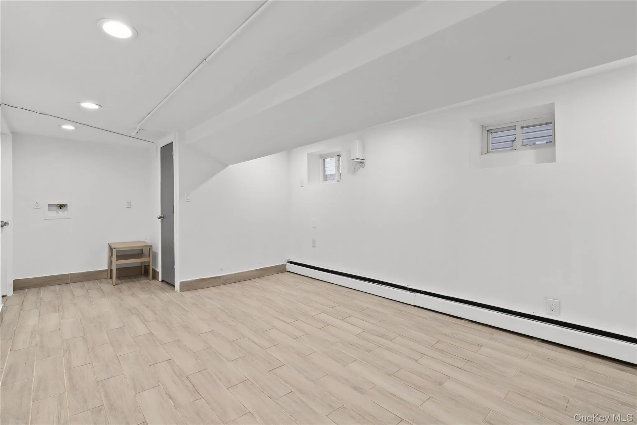 Below grade area featuring baseboard heating, light wood-style flooring, and recessed lighting Below grade area featuring baseboard heating, light wood-style flooring, and recessed lighting