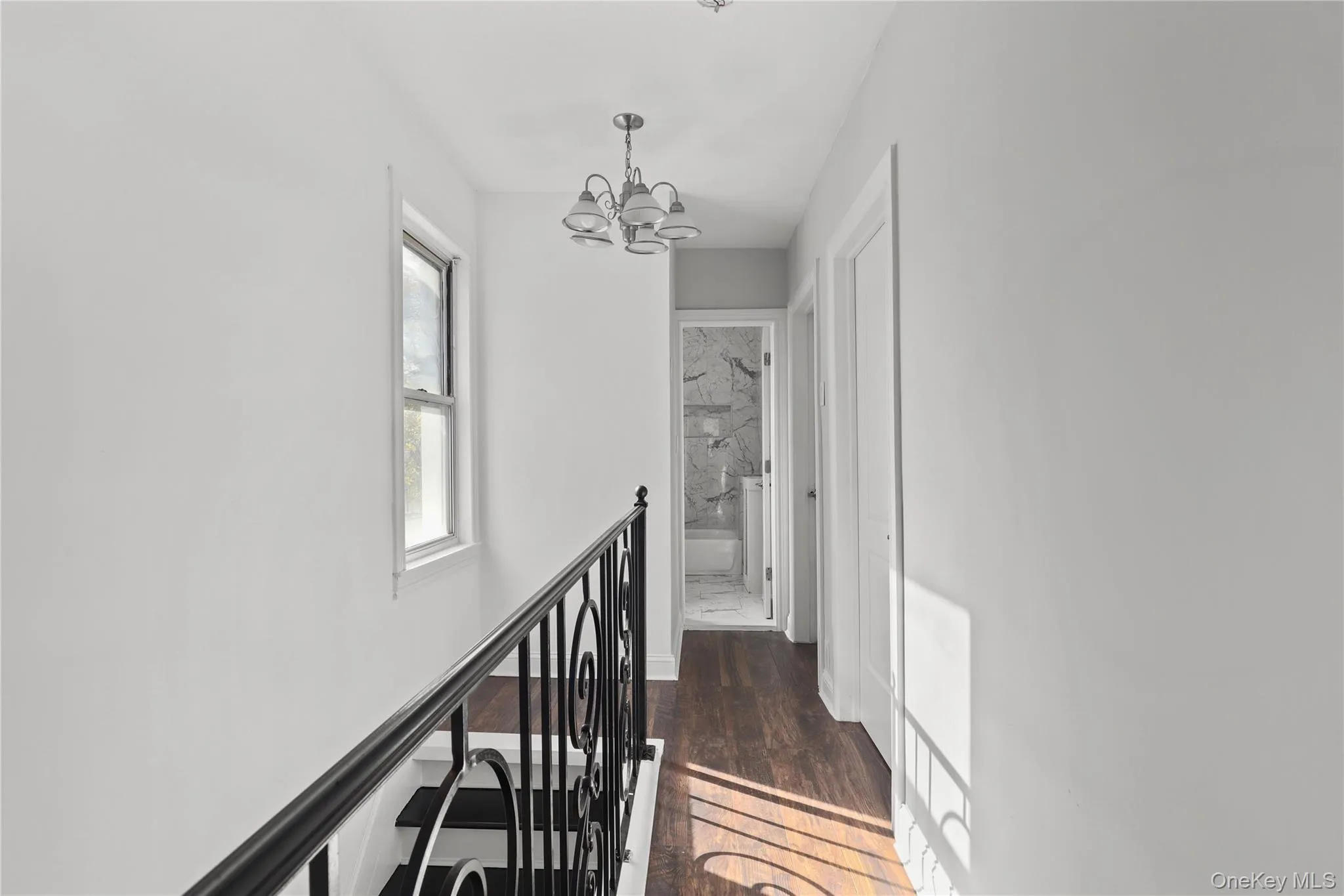 Hall with an upstairs landing, a chandelier, and dark wood-type flooring Hall with an upstairs landing, a chandelier, and dark wood-type flooring