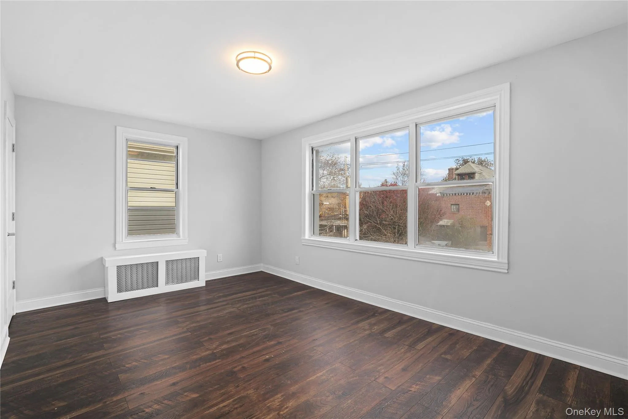Empty room featuring radiator heating unit and dark wood-style floors Empty room featuring radiator heating unit and dark wood-style floors