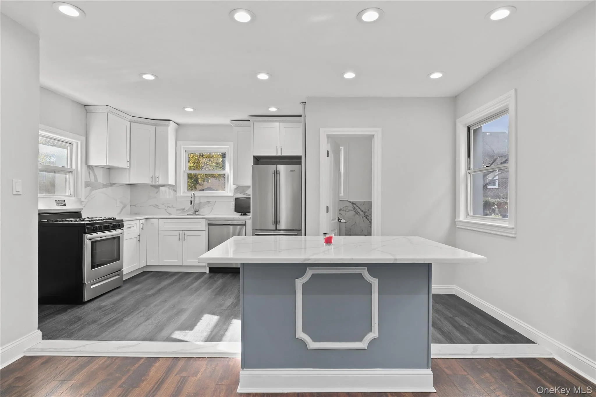 Kitchen with appliances with stainless steel finishes, white cabinets, light stone countertops, decorative backsplash, and recessed lighting Kitchen with appliances with stainless steel finishes, white cabinets, light stone countertops, decorative backsplash, and recessed lighting