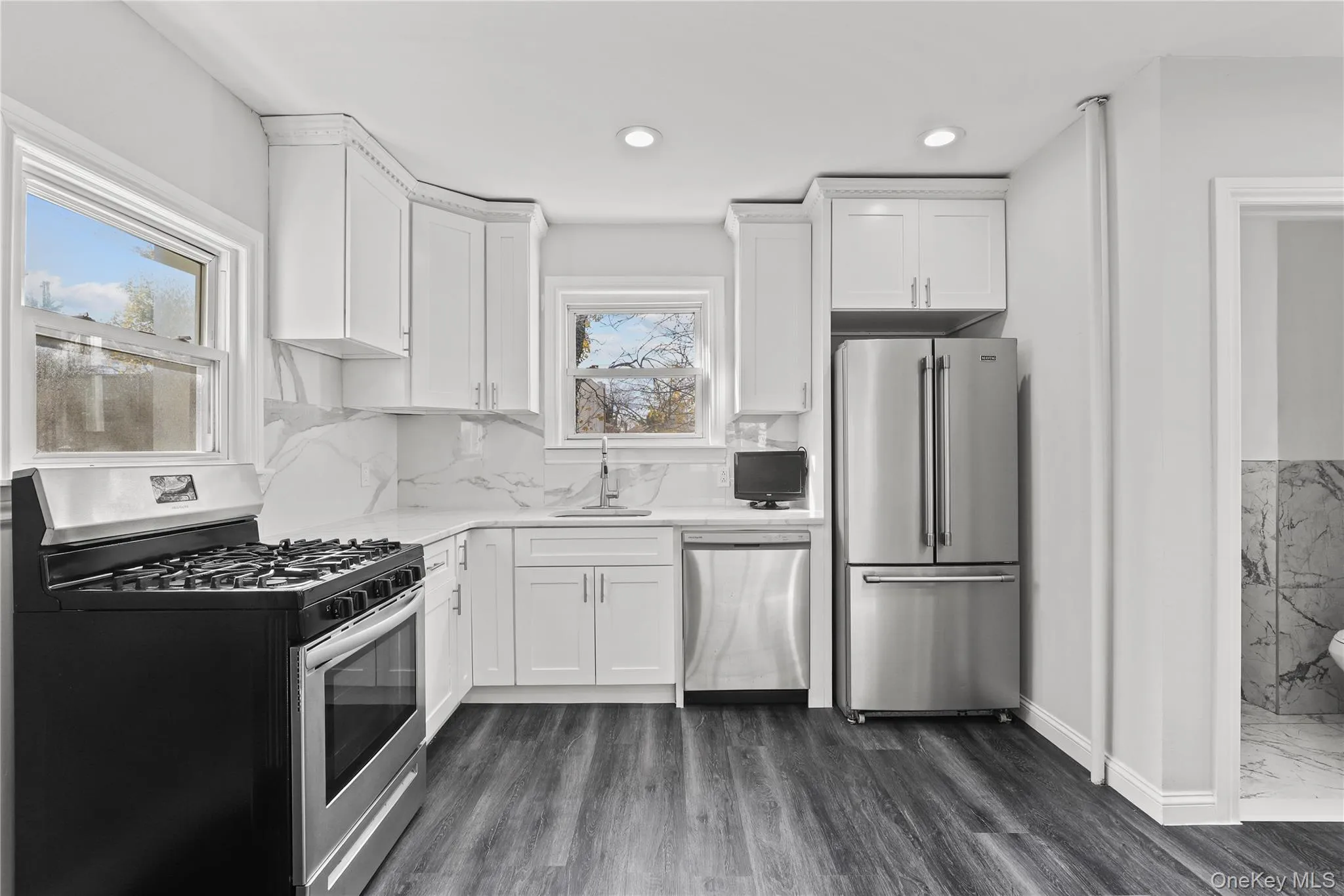Kitchen featuring stainless steel appliances, white cabinetry, dark wood-style flooring, and recessed lighting Kitchen featuring stainless steel appliances, white cabinetry, dark wood-style flooring, and recessed lighting