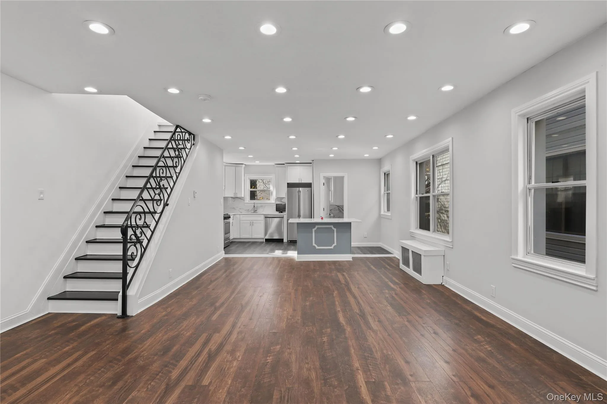 Unfurnished living room with stairs, recessed lighting, dark wood-style floors, and radiator Unfurnished living room with stairs, recessed lighting, dark wood-style floors, and radiator