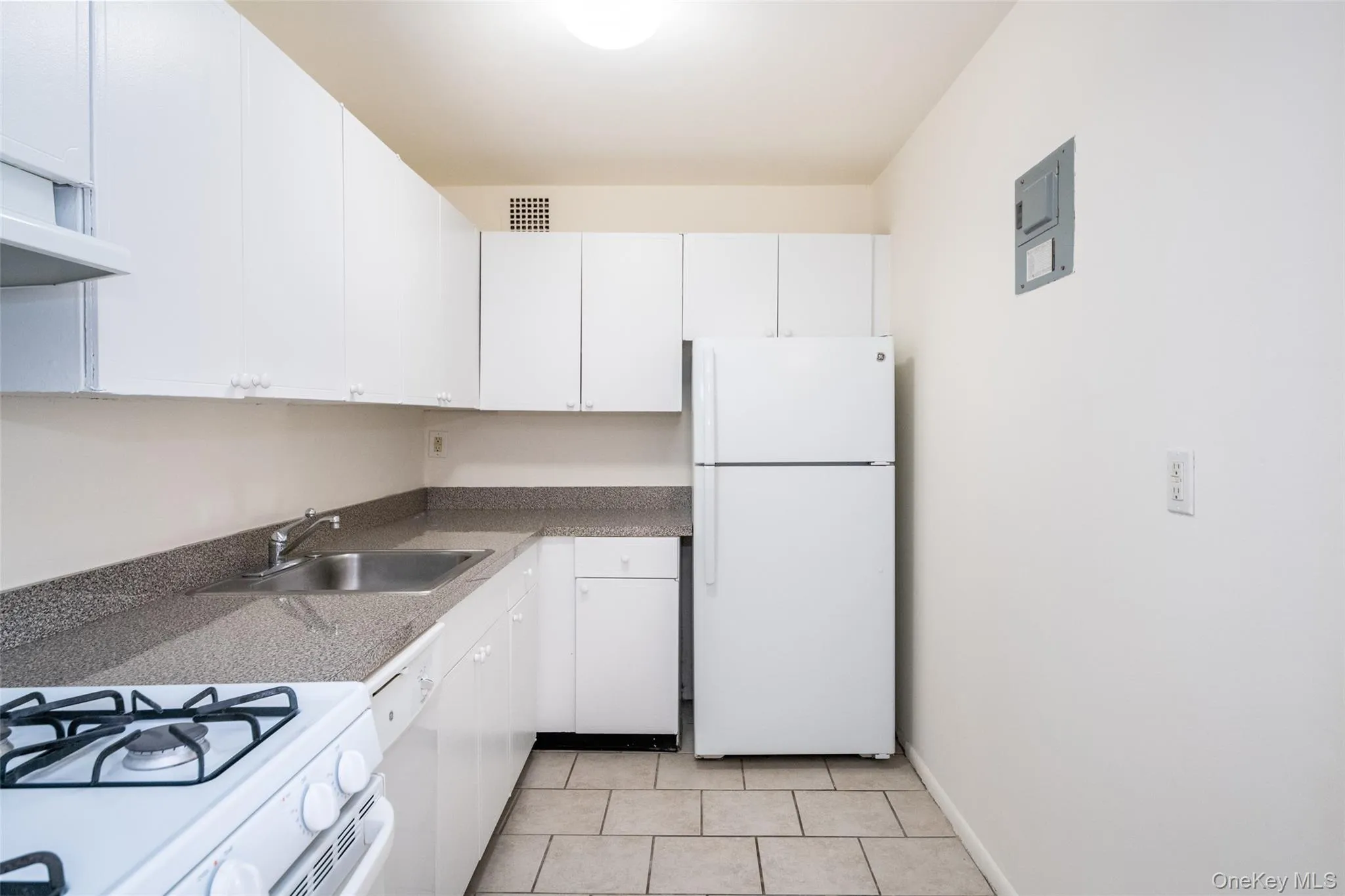 Kitchen featuring white appliances, white cabinetry, and light tile patterned flooring Kitchen featuring white appliances, white cabinetry, and light tile patterned flooring