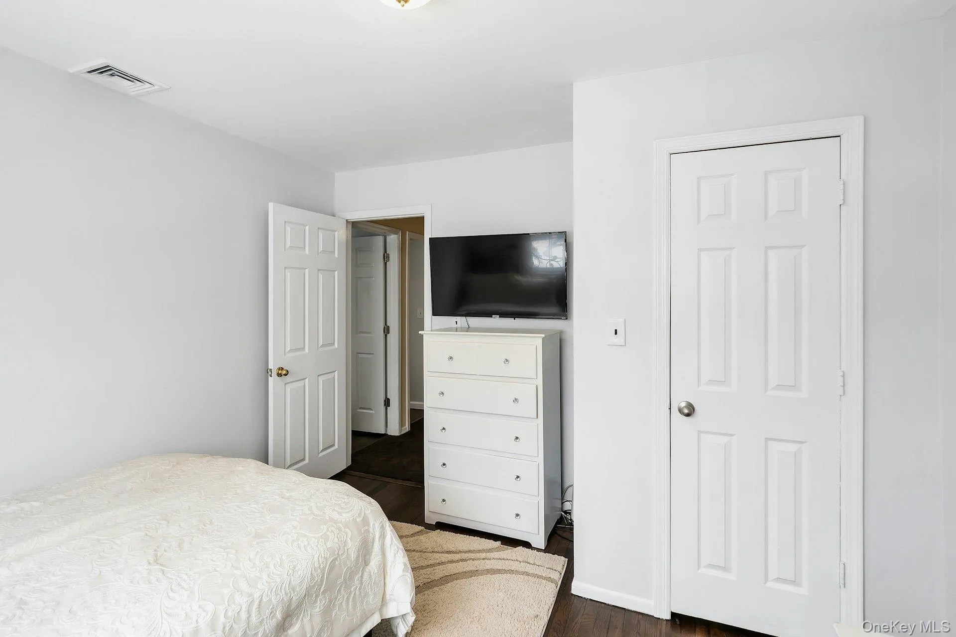 Bedroom with dark wood finished floors and baseboards Bedroom with dark wood finished floors and baseboards
