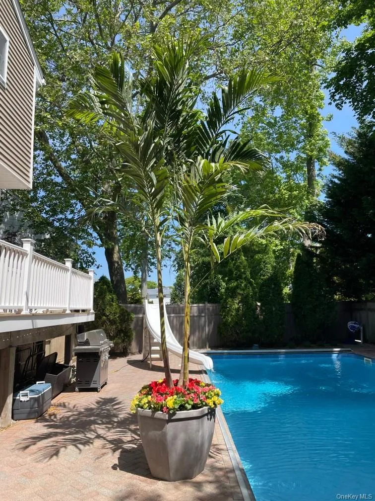 View of pool with a water slide, a fenced backyard, grilling area, and patio surround View of pool with a water slide, a fenced backyard, grilling area, and patio surround