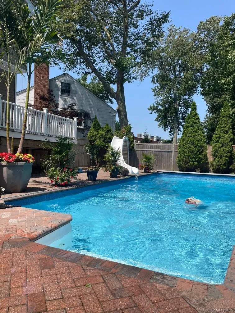 View of pool featuring a water slide, a fenced backyard, and patio surround View of pool featuring a water slide, a fenced backyard, and patio surround