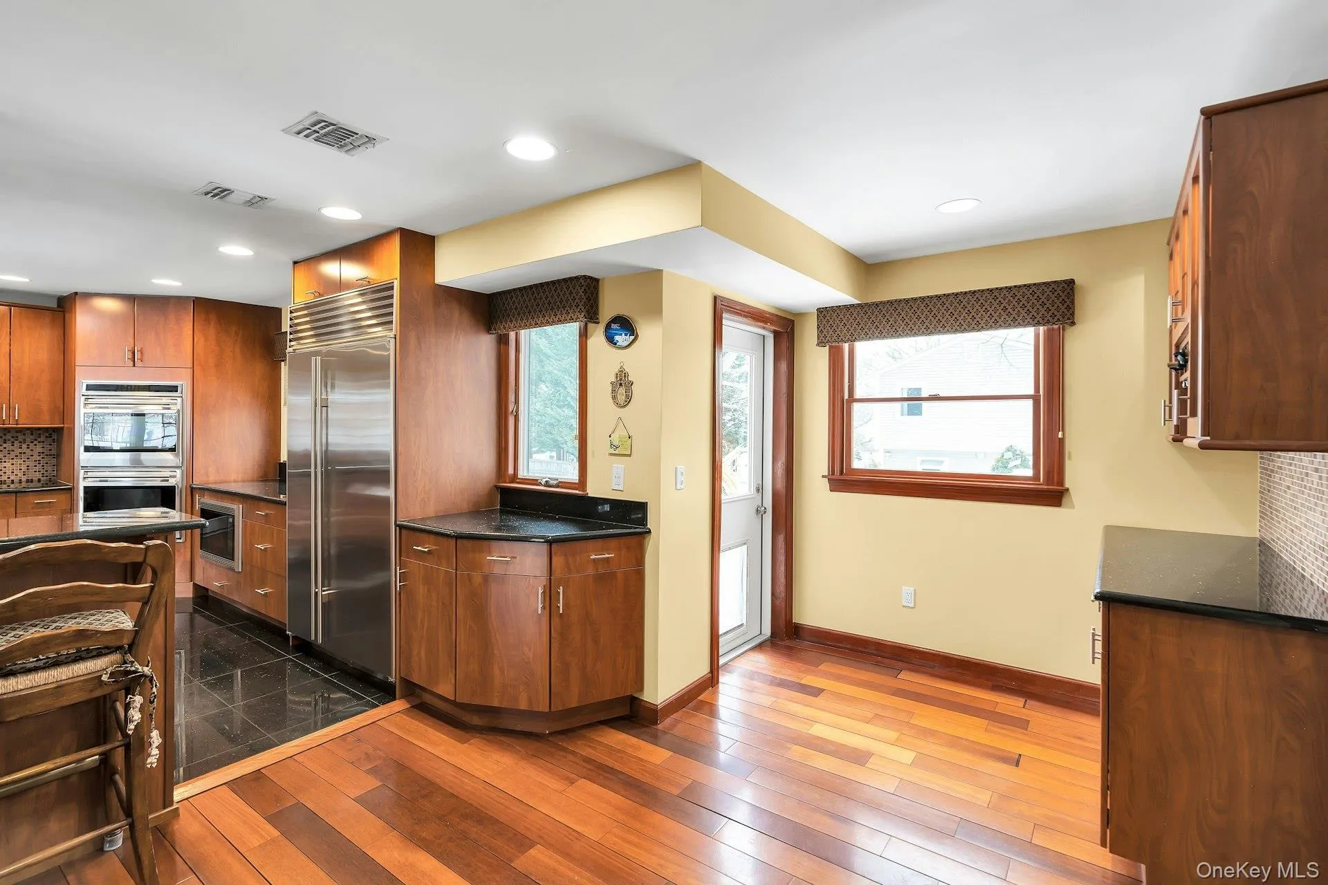 Kitchen with decorative backsplash, wood finish cabinets, stainless steel appliances, dark wood-type flooring, and recessed lighting Kitchen with decorative backsplash, wood finish cabinets, stainless steel appliances, dark wood-type flooring, and recessed lighting