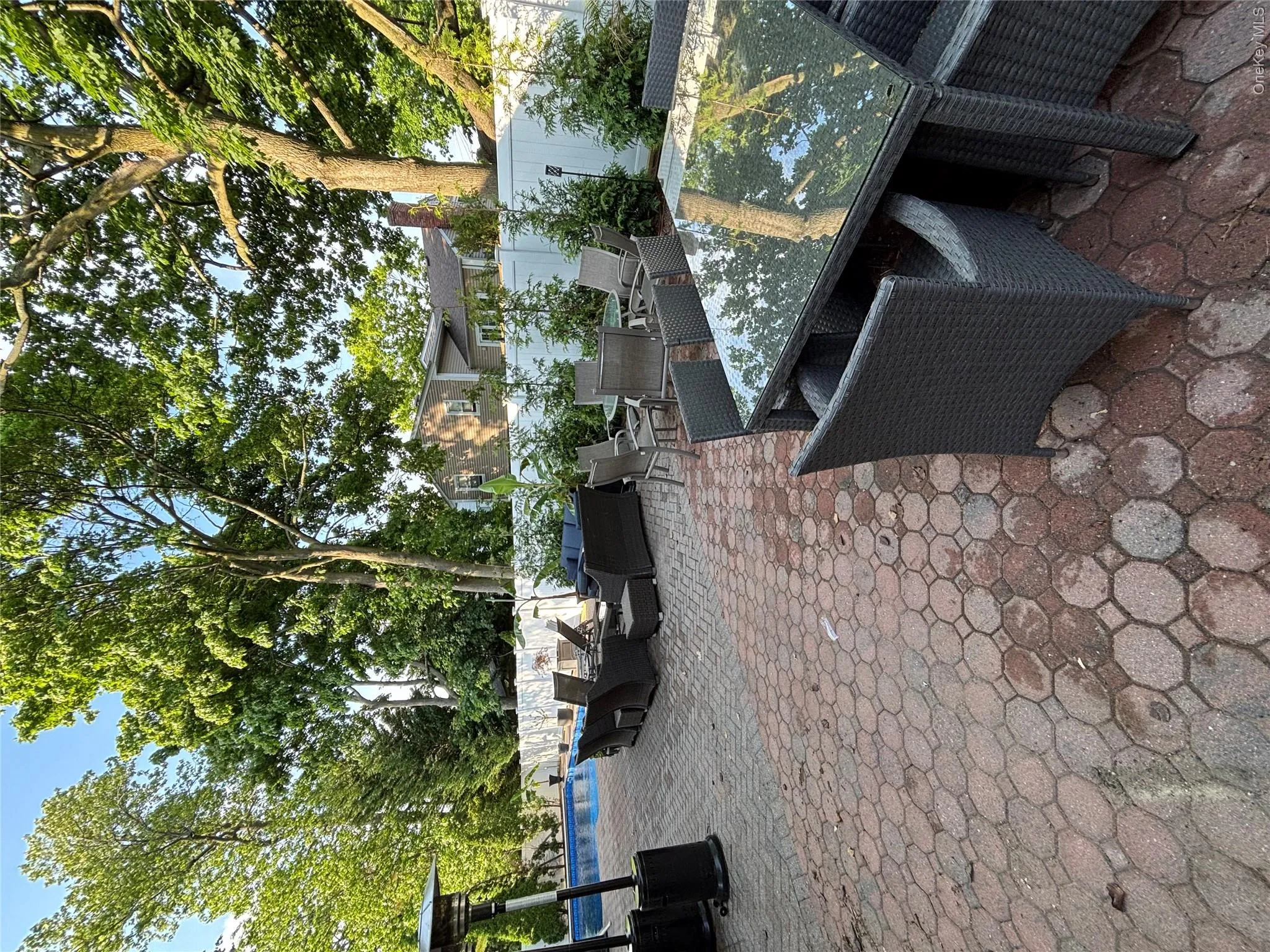Expansive paver patio with a white privacy fence and mature trees Expansive paver patio with a white privacy fence and mature trees