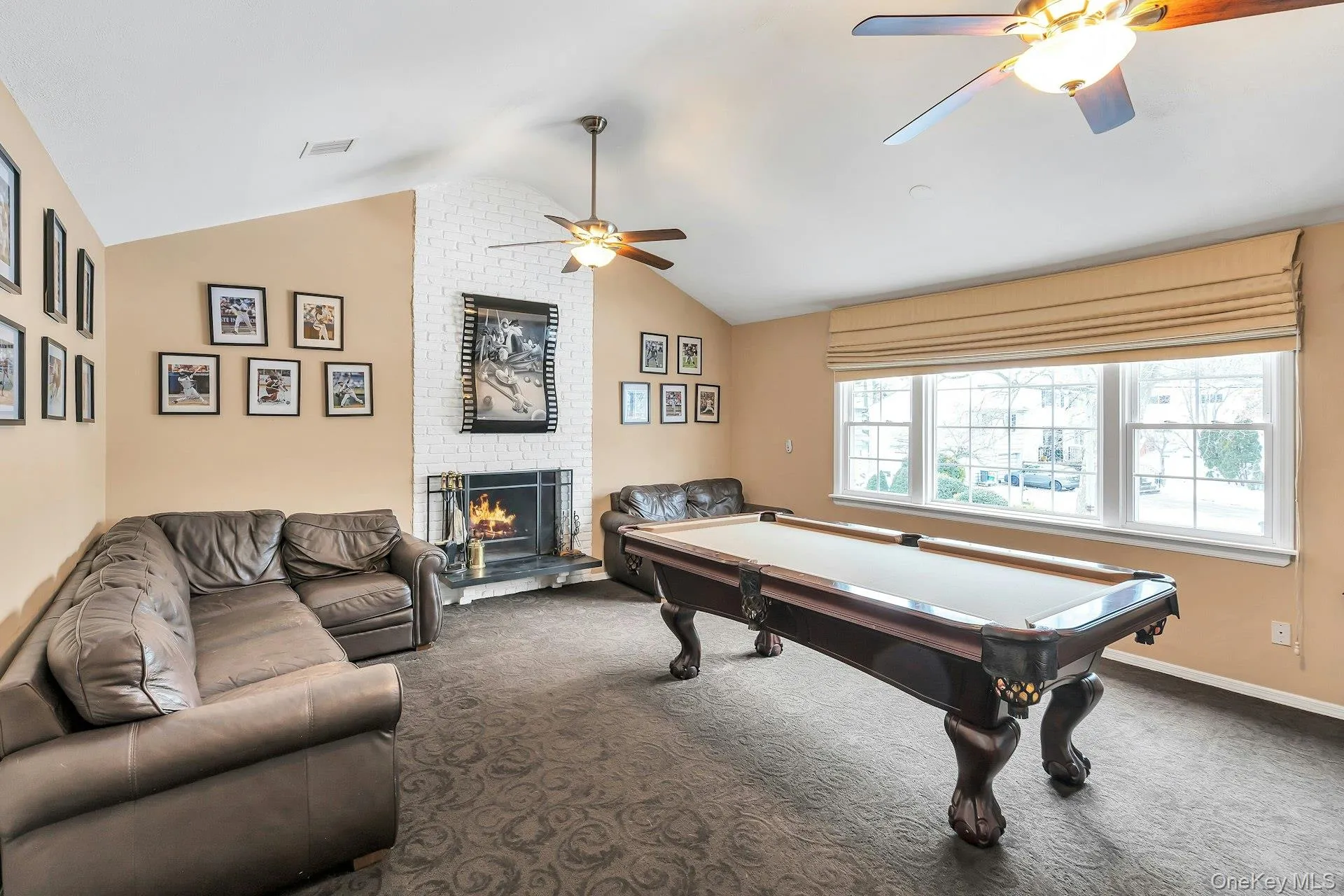 Living room featuring carpet flooring, a brick fireplace, ceiling fan, and pool table Living room featuring carpet flooring, a brick fireplace, ceiling fan, and pool table