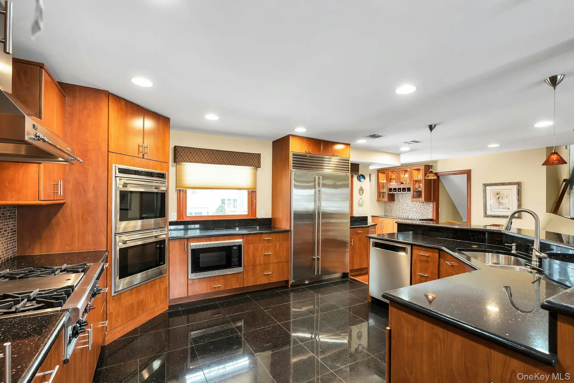 Kitchen with built in appliances, pendant lighting, dark stone countertops, wood finish cabinetry, and decorative backsplash Kitchen with built in appliances, pendant lighting, dark stone countertops, wood finish cabinetry, and decorative backsplash