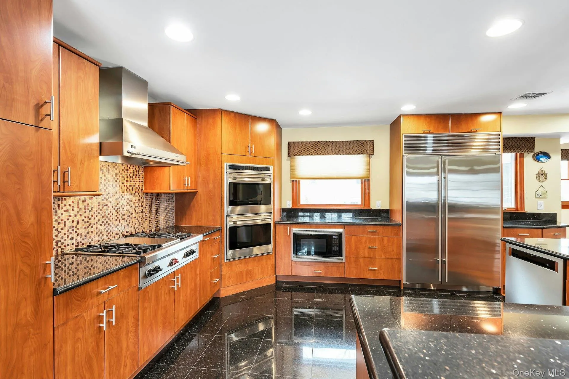Kitchen with built in appliances, granite tiled floors, wood finish cabinetry, dark stone counters, and recessed lighting Kitchen with built in appliances, granite tiled floors, wood finish cabinetry, dark stone counters, and recessed lighting