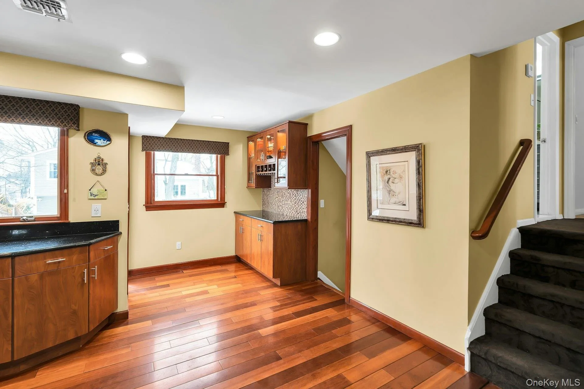 Kitchen featuring wood finish cabinets, light wood-style flooring, decorative backsplash, and dark stone countertops Kitchen featuring wood finish cabinets, light wood-style flooring, decorative backsplash, and dark stone countertops