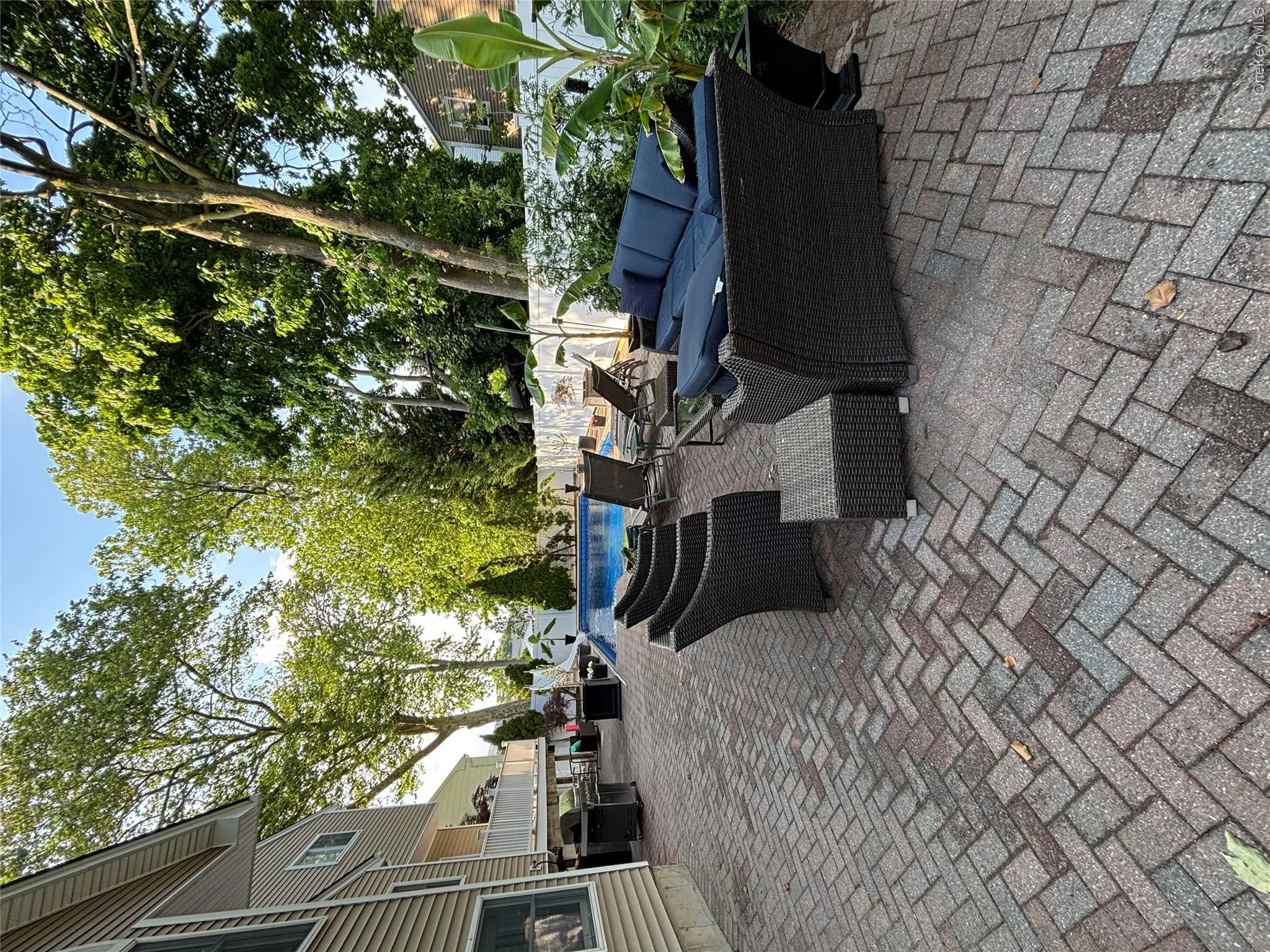 Spacious brick paver patio featuring a swimming pool, privacy fencing, and mature trees Spacious brick paver patio featuring a swimming pool, privacy fencing, and mature trees