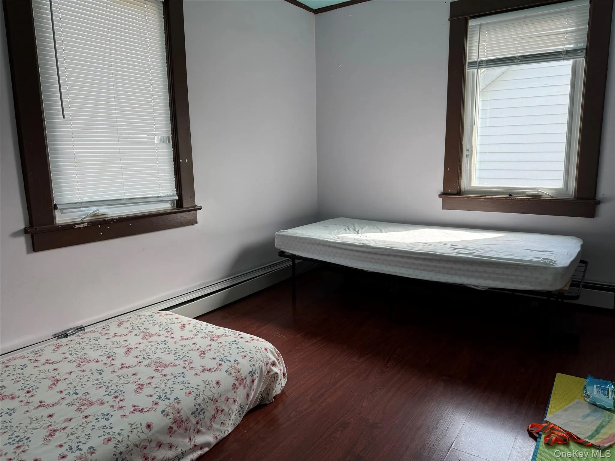 Bedroom with wood finished floors and a baseboard heating unit Bedroom with wood finished floors and a baseboard heating unit