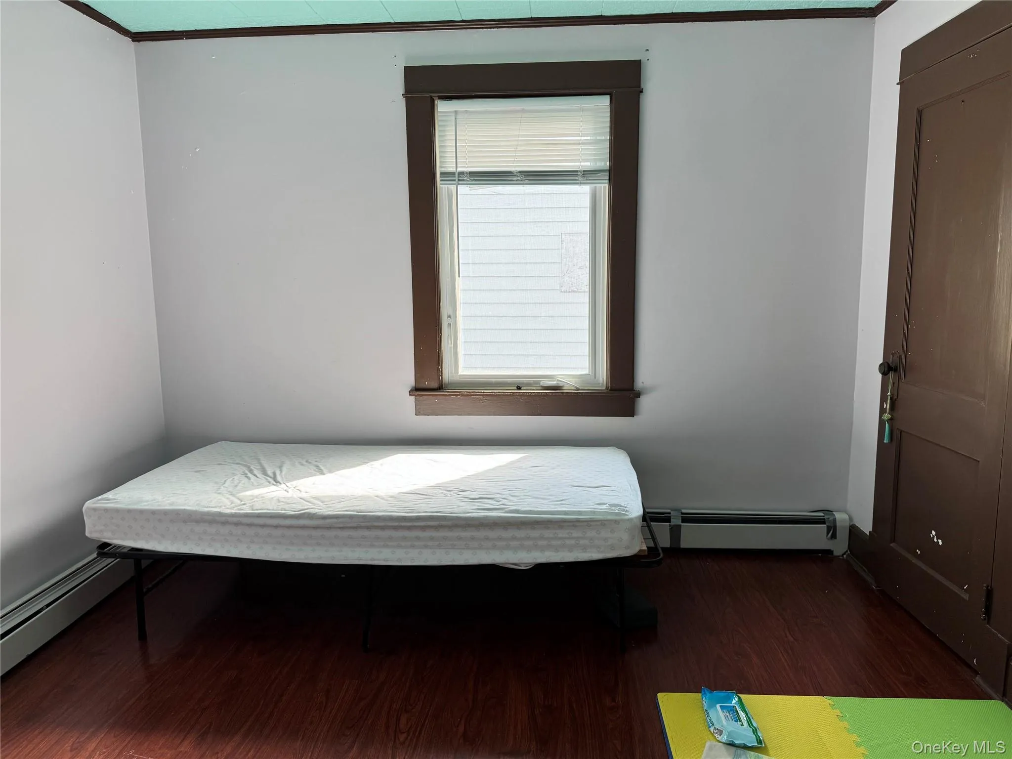 Bedroom with baseboard heating and wood finished floors Bedroom with baseboard heating and wood finished floors